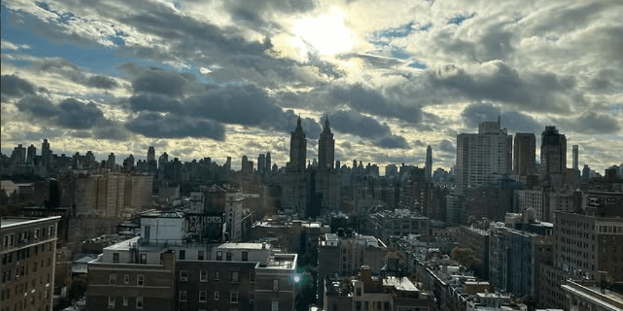 A dramatic Upper West Side skyline under a bright, clouded sky.